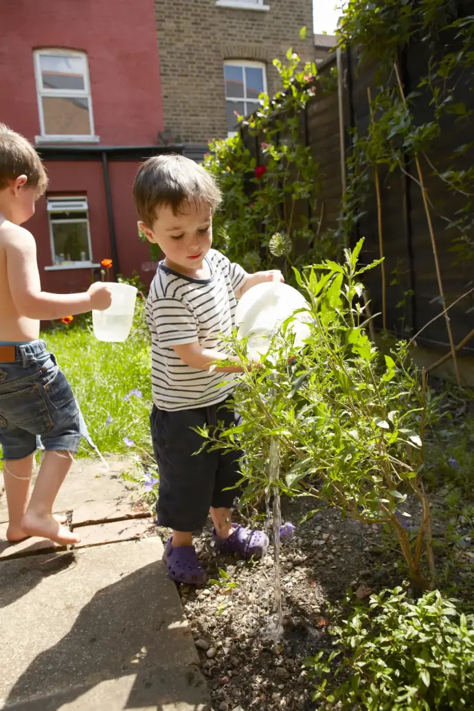 Dos niños regando las plantas de su jardín