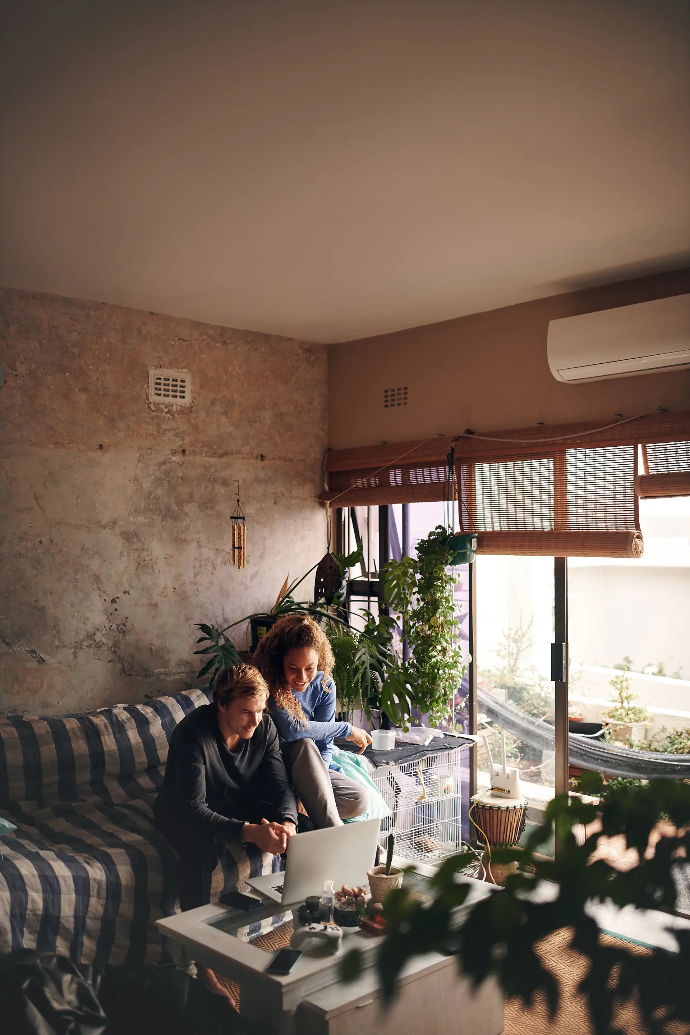 Pareja sentada en el sillon de su casa mirando el ordenador