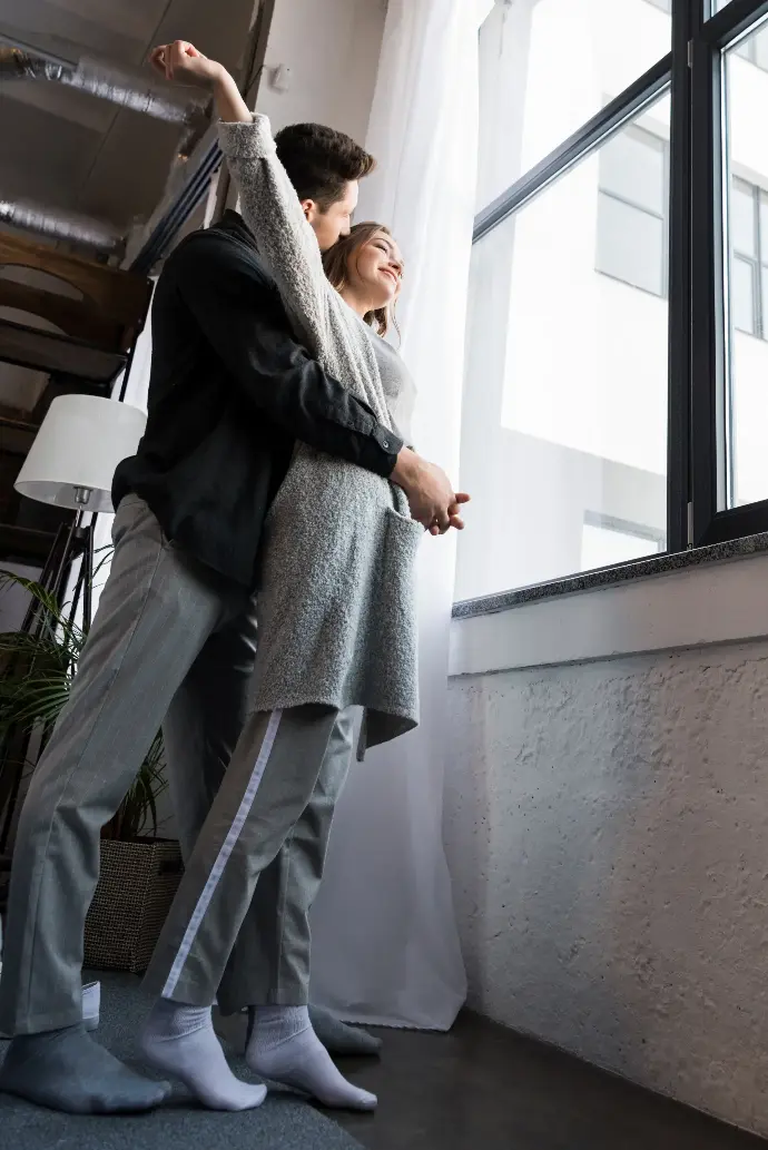 Pareja joven frente a una ventada en su piso.