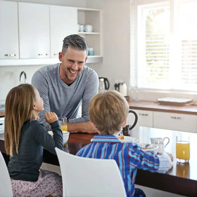 Hombre con sus dos hijos desayunando en la cocina